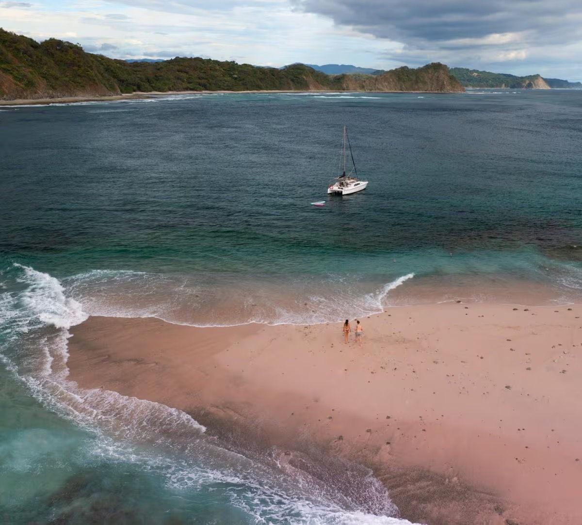 Secluded Costa Rica beach with catamaran offshore