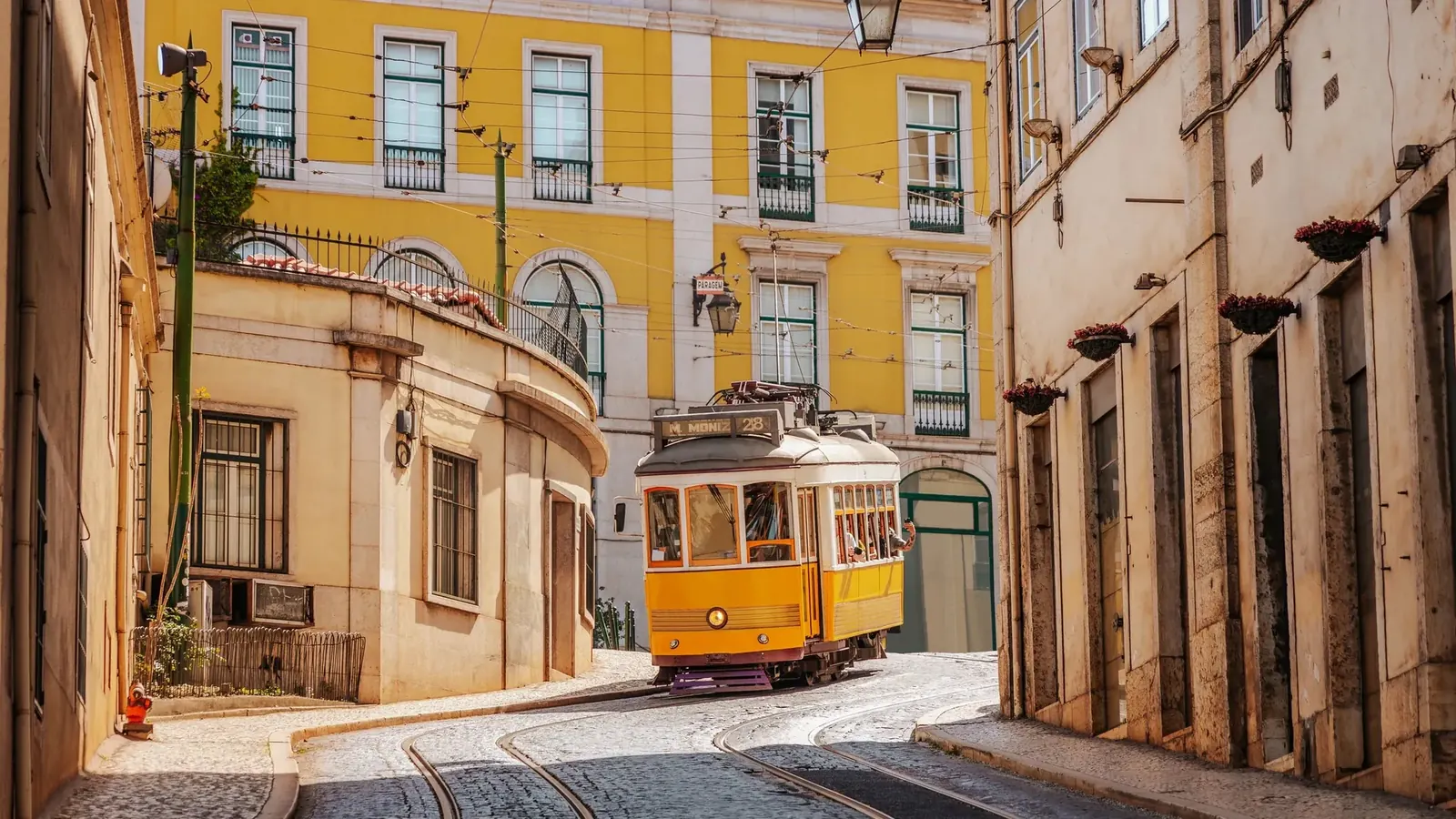 Yellow tram on a sunlit street in Lisbon, Portugal